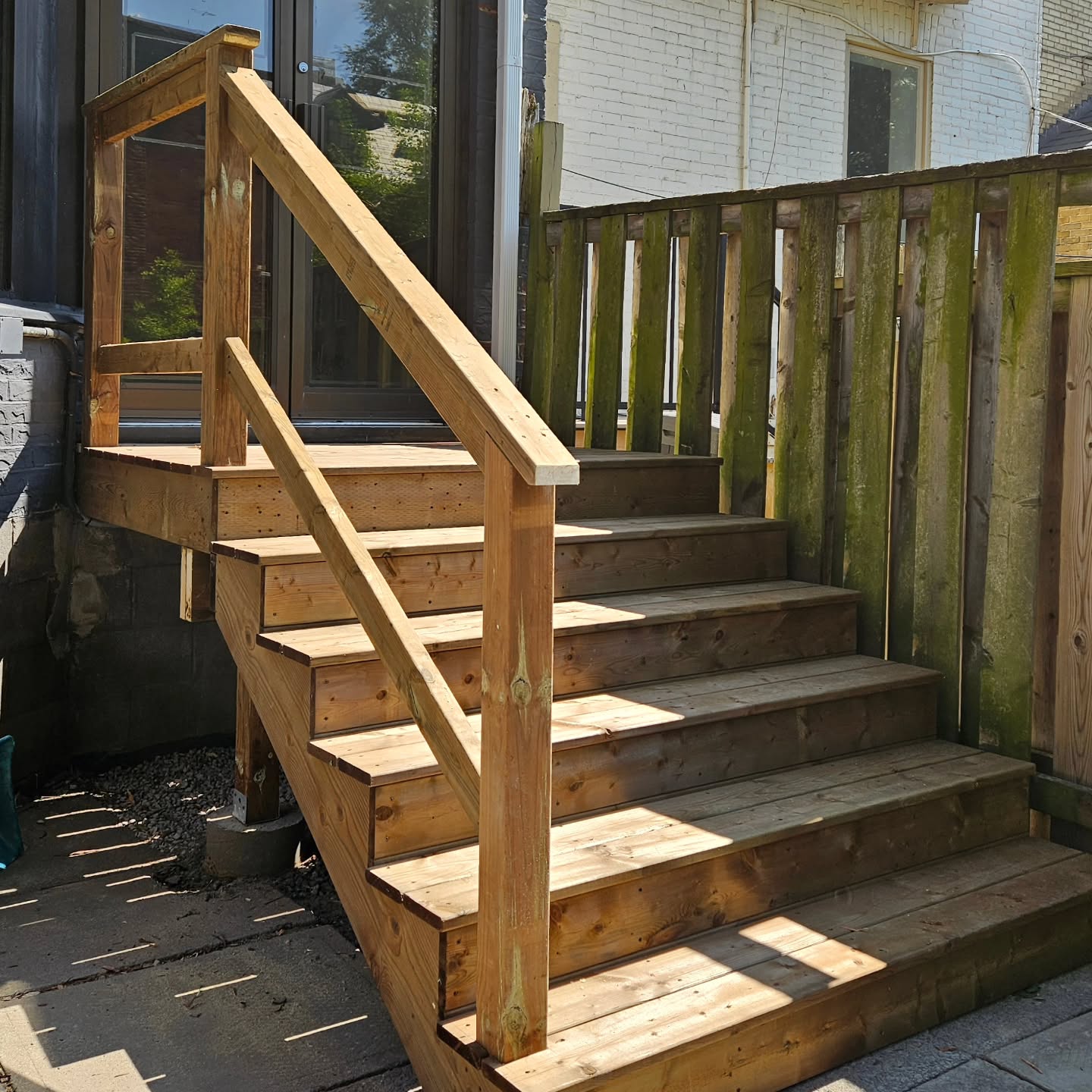 The finished wood stairs and handrail seen from the side, with new treads and risers in place